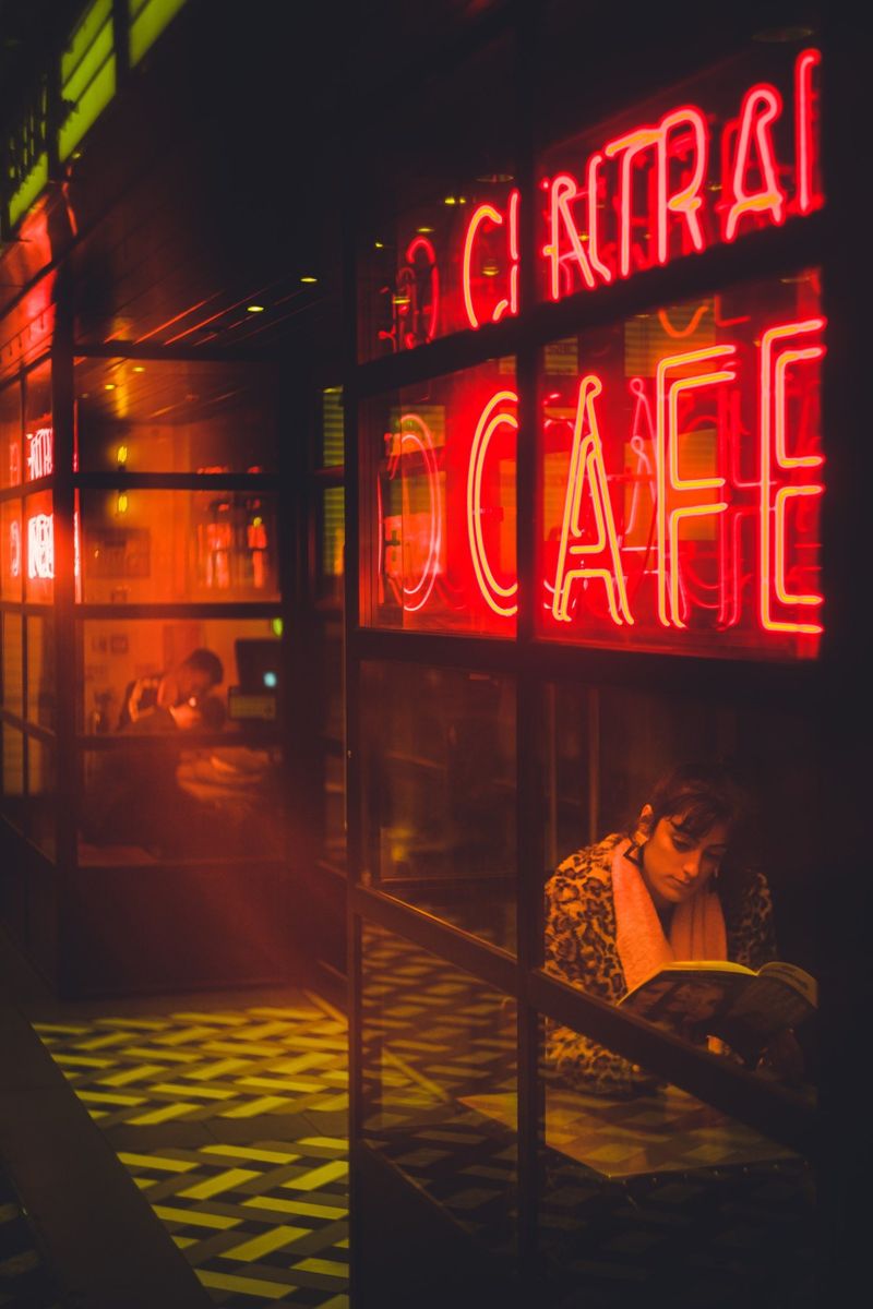 Mulher a ler junto ao néon vermelho de um café
