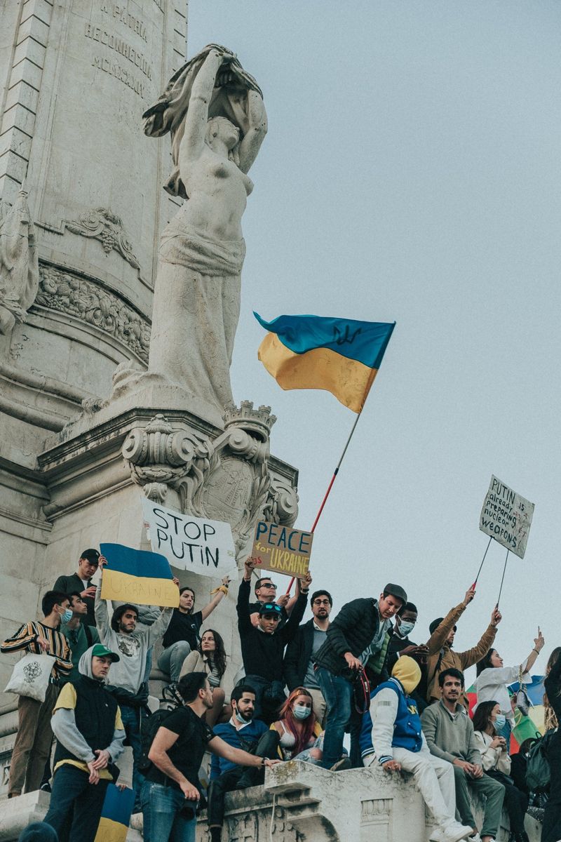 Manifestantes com bandeiras da Ucrânia num monumento
