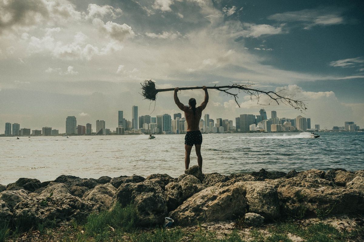 Homem ergue um ramo diante do skyline da cidade